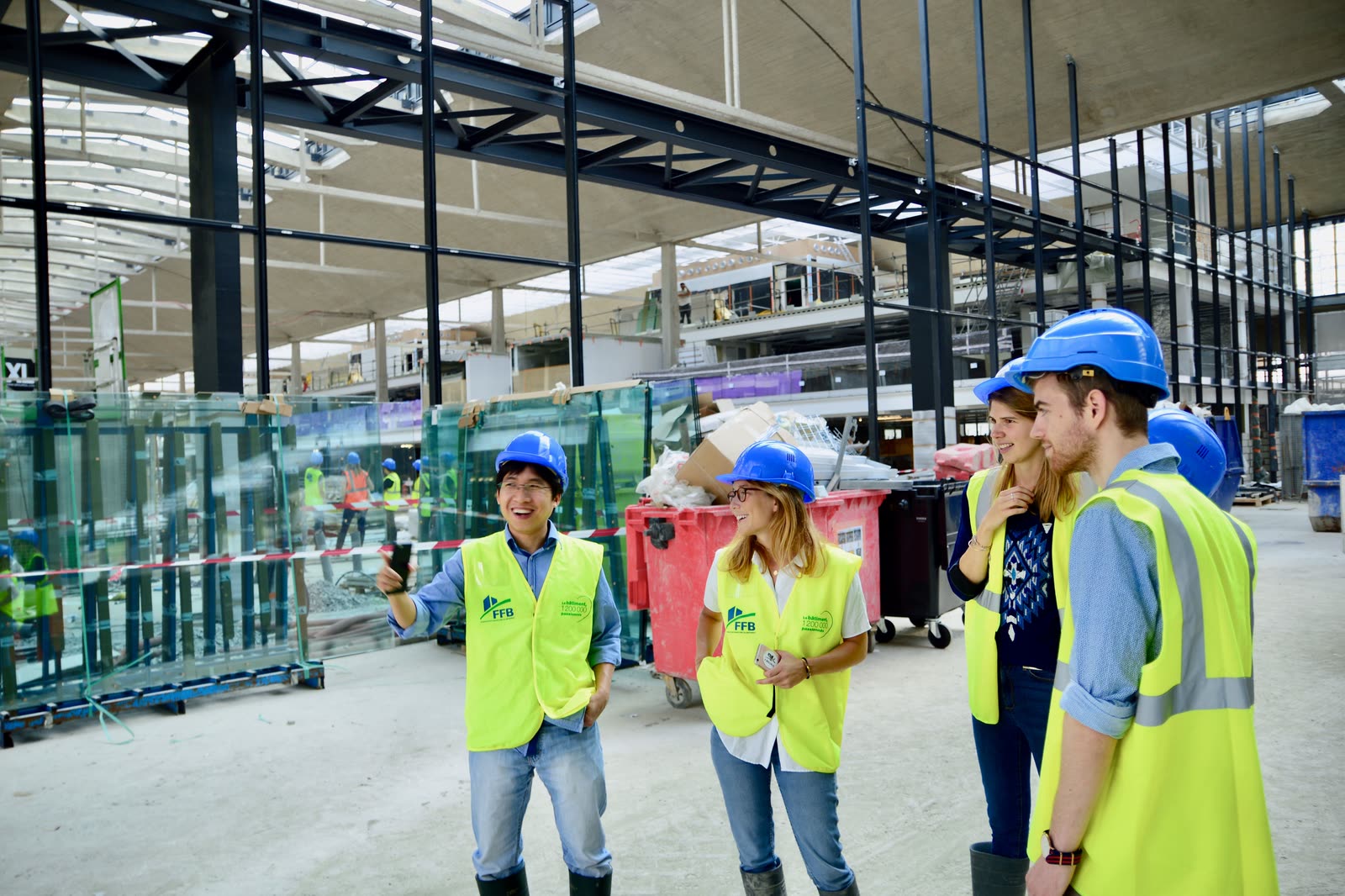 A group of engineers in vests and hard hats talking on a site.