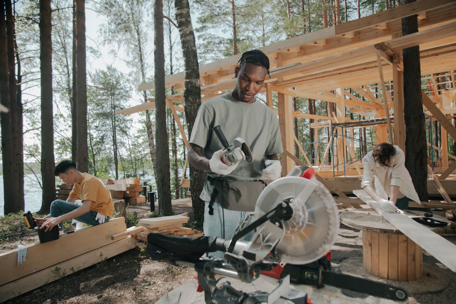 A crew building a timber structure among tall trees.